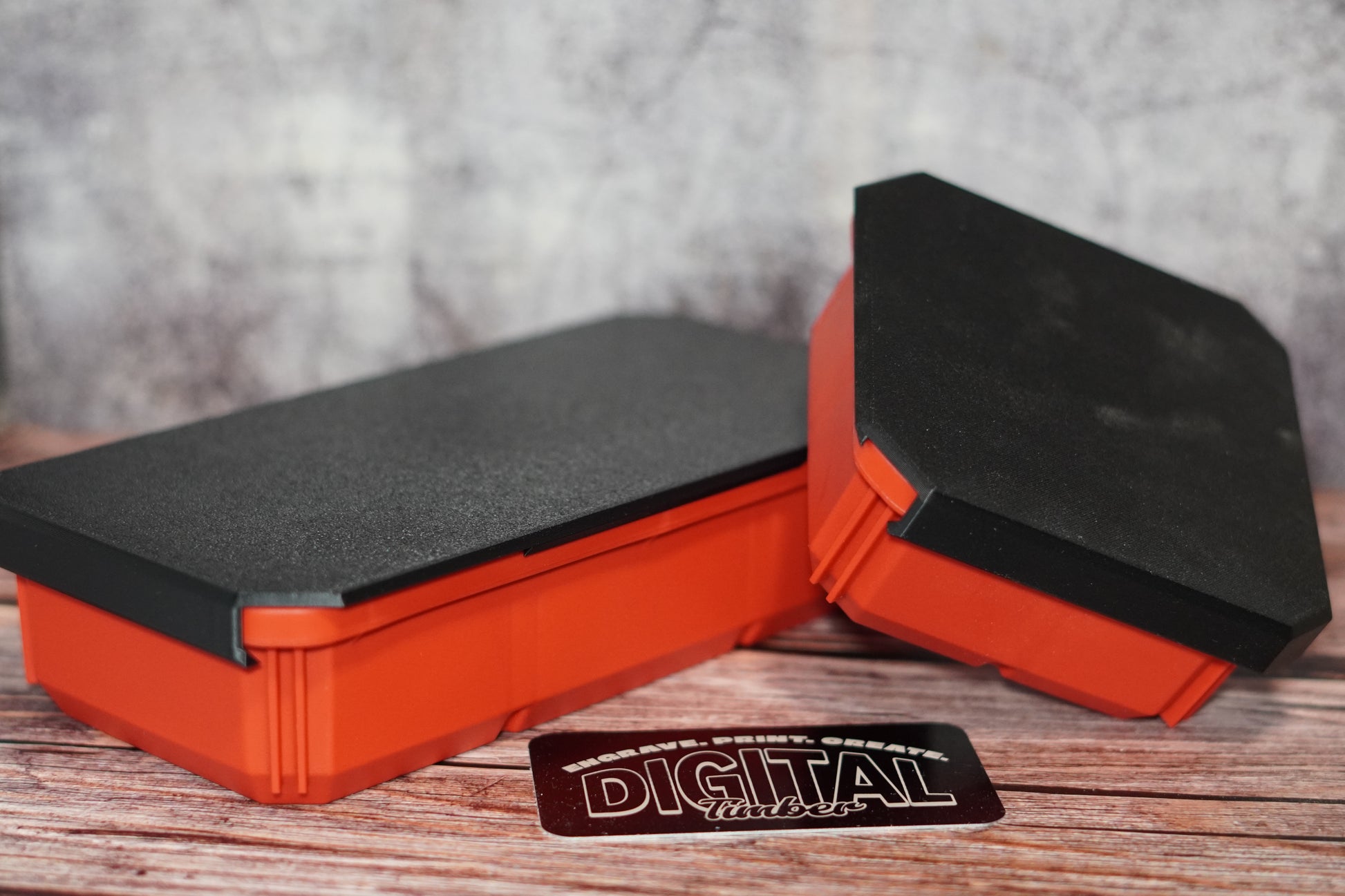 Four orange and black Milwaukee Packout bin covers placed on a wooden surface, with the brand name 'Digital' visible on a tag in the foreground.